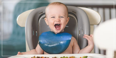 Laughing baby in a high chair, nursing and feeding