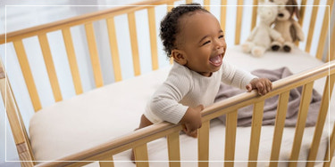 Baby laughing in a crib, nursery and home