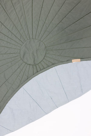 Linen quilted playmat in Acadian/Dove color, angled view showcasing soft texture and design for baby playtime.
