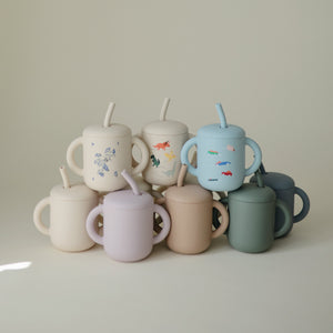 Silicone training cup with straw, angled view, perfect for toddlers learning to drink independently.