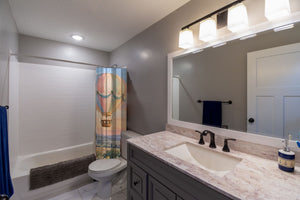 Sunset Flight Hot Air Balloon shower curtain pulled open in a gray kids bathroom