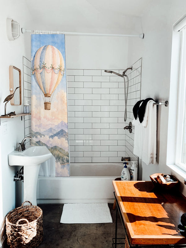 Mountain Hot Air Balloons shower curtain hanging on the rod over a white bathtub