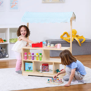 Holly Wooden Market Stand for kids' pretend play, featuring a display shelf in a charming indoor setting.
