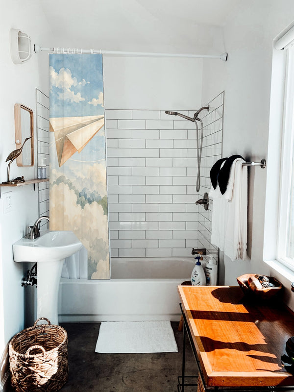 Paper Planes shower curtain hanging on the rod over a white bathtub