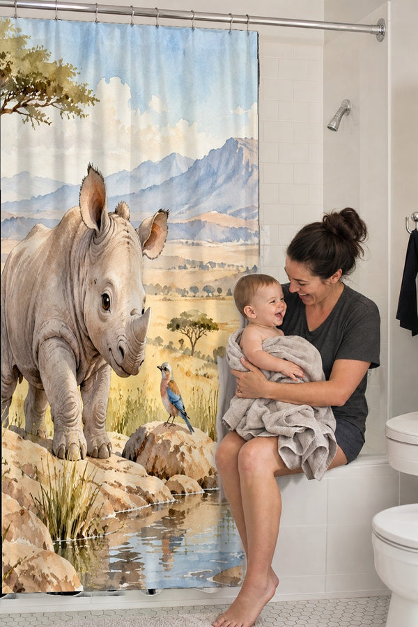 Mom holding her baby on the tub edge next to the Baby Rhino Safari shower curtain