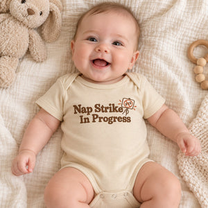 Baby wearing the Nap Strike In Progress baby bodysuit