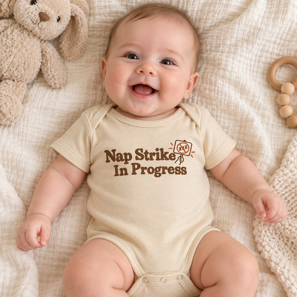 Baby wearing the Nap Strike In Progress baby bodysuit