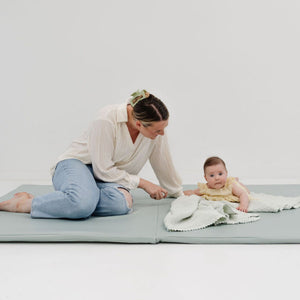 Sage vegan leather play mat for babies, stylish and soft, angled view showcasing its design and texture.