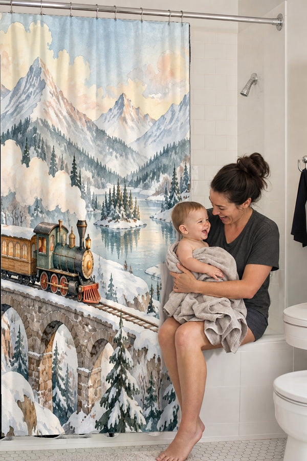 Mom holding her baby on the tub edge next to the Winter Train shower curtain