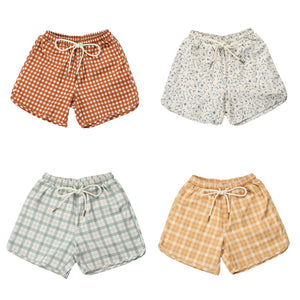Baby swim trunks in buckwheat plaid, UPF protected and made from recycled materials, angled view.