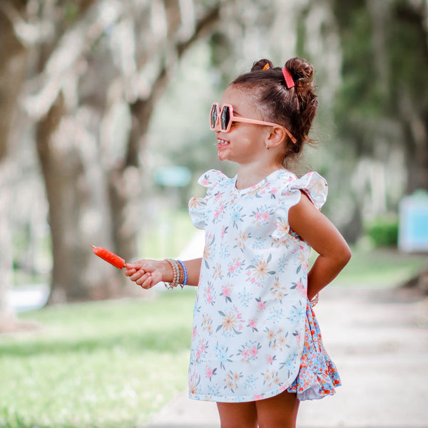 Pastel Floral Flutter Bapron for babies, featuring a charming floral design and flutter sleeves, angled view.