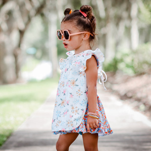 Pastel Floral Flutter Bapron for babies, angled view showcasing vibrant floral design and flutter sleeves.