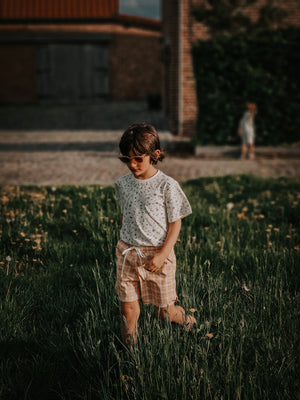 Baby swim trunks in buckwheat plaid, UPF protected and made from recycled materials, angle view.