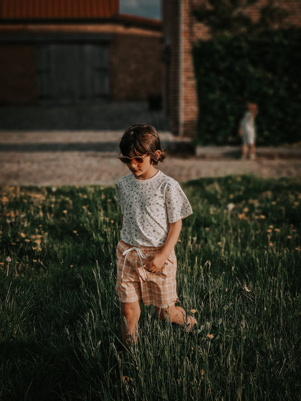 Baby swim trunks in buckwheat plaid, UPF protected and made from recycled materials, angle view.