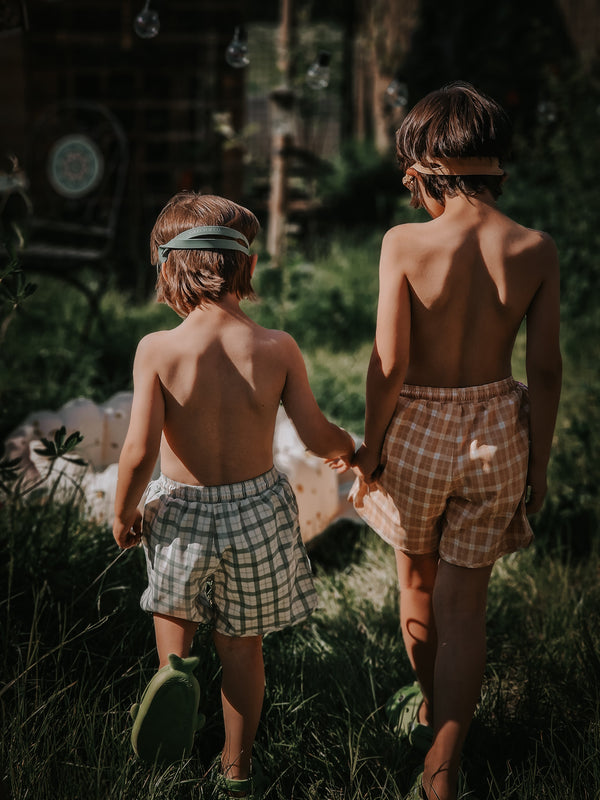 Baby swim trunks in Buckwheat Plaid, UPF protection, made from recycled materials, angle view.