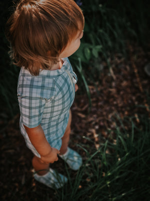 Short Sleeve Rashguard Swimsuit in Fern Plaid, UPF protection, eco-friendly, angle view. Perfect for baby beach days.