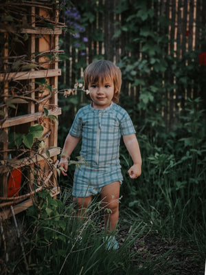 Short sleeve rashguard swimsuit in fern plaid, UPF protection, eco-friendly, angle view. Perfect for baby beach days.