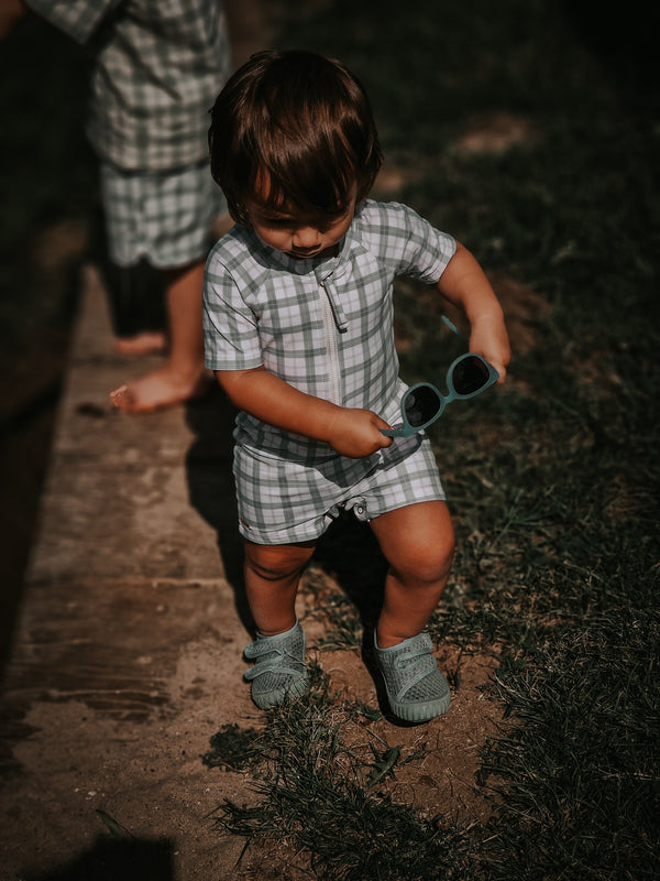 Short Sleeve Rashguard Swimsuit in Fern Plaid, UPF protection, eco-friendly, angled view. Perfect for baby beach fun.