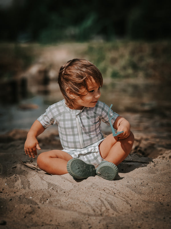 Short sleeve rashguard swimsuit in fern plaid, UPF protection, eco-friendly, angled view. Perfect for baby swimwear.