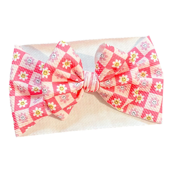 Pink checkered floral baby bow accessory for stylish seasonal wear.