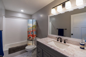 Fire Truck Town shower curtain pulled open in a gray kids bathroom
