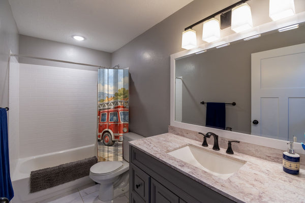 Fire Truck Town shower curtain pulled open in a gray kids bathroom