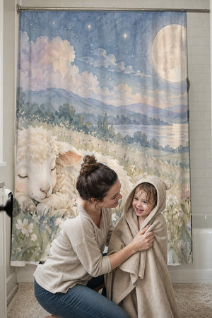 Mom drying her toddler in a hooded towel in front of the Meadow Lamb shower curtain