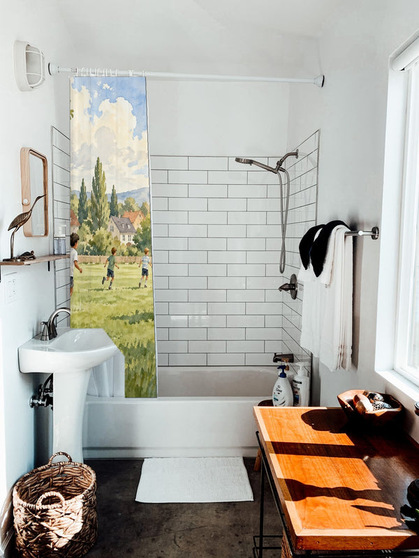 Kids Playing Soccer shower curtain hanging on the rod over a white bathtub