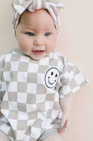 Short Sleeve Bubble Romper in Checkered Smiley Latte for babies, stylish and comfy for warm days.