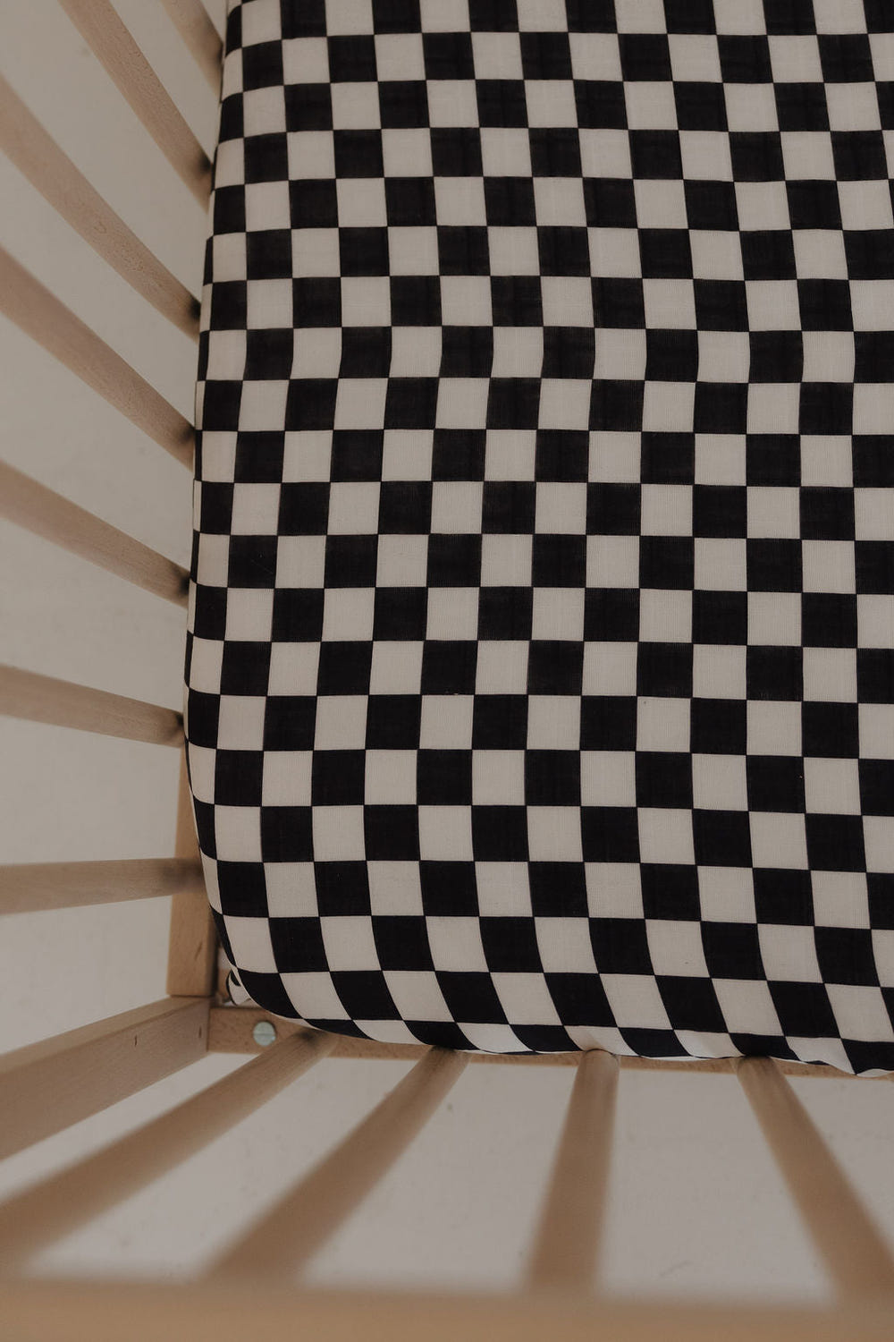 Black and white checkerboard muslin crib sheet for stylish nursery decor. Soft, breathable, and perfect for baby’s crib.