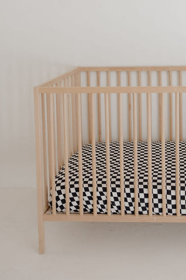 Black and white checkerboard muslin crib sheet for stylish nursery decor. Soft, breathable, and perfect for baby’s crib.