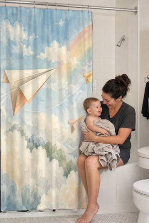 Mom holding her baby on the tub edge next to the Paper Planes shower curtain