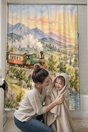 Mom drying her toddler in a hooded towel in front of the Sunrise Train shower curtain