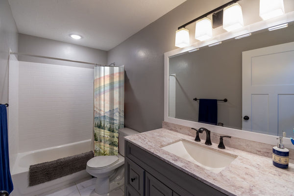 Mountain River Rainbow shower curtain pulled open in a gray kids bathroom