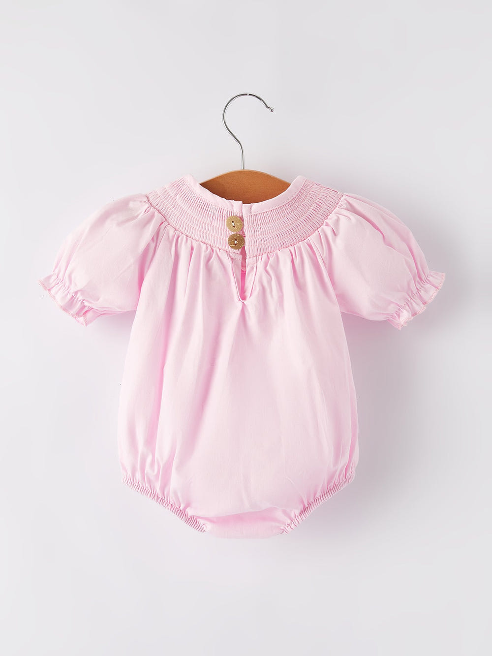 White bow smock embroidered pink romper for babies, perfect for stylish and comfortable playtime.