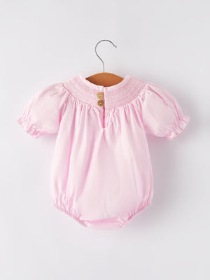 White bow smock embroidered pink romper for babies, angle view showcasing delicate design and soft fabric.