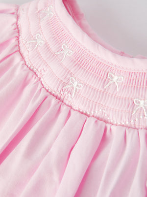 White bow smock embroidered pink romper for babies, angle view showcasing cute design and details.
