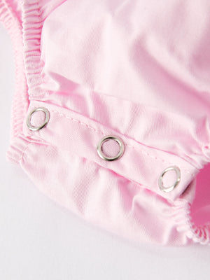 White bow smock embroidered pink romper for babies, angle view showcasing its cute design and soft fabric.