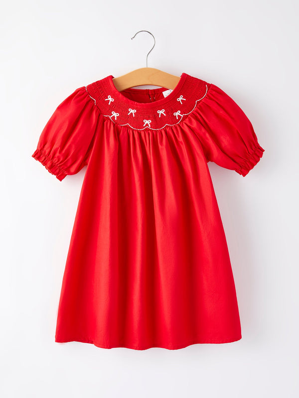 Girls red dress with bow smocking and embroidery, shown from angle 3. Perfect for special occasions.