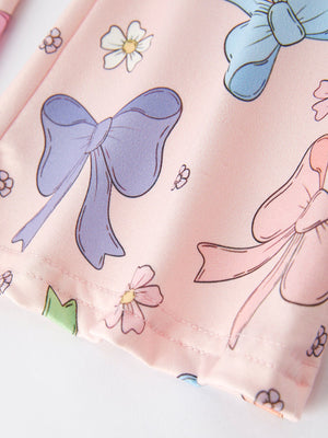 Purple girls' top with bow and floral print, paired with bell bottom pants, showcased at angle 3.