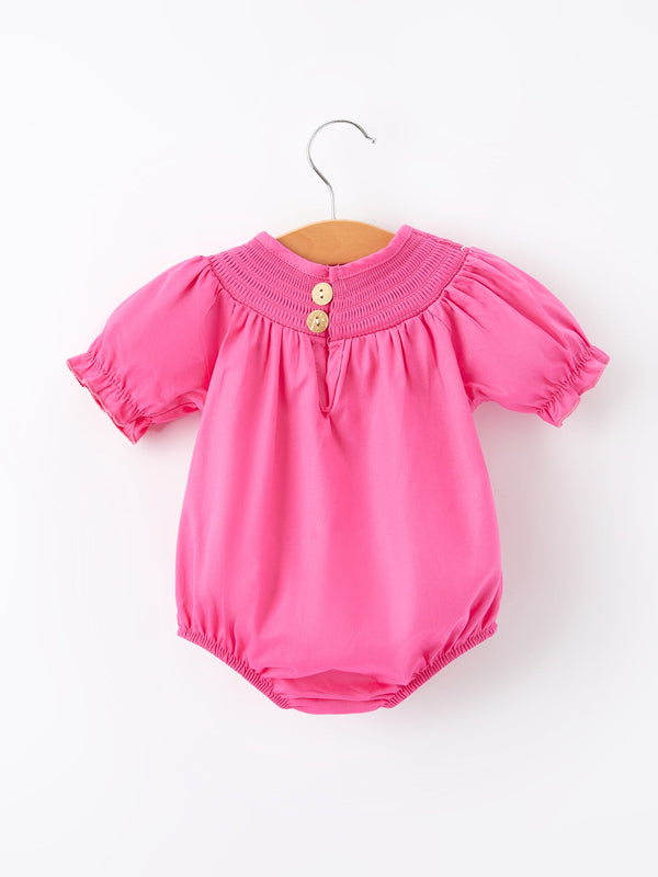 Girls hot pink romper with bow smocking embroidery, shown from angle 2. Perfect for stylish little ones!