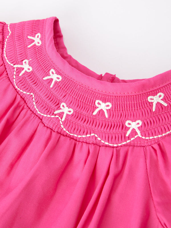 Girls hot pink romper with bow smocking embroidery, shown from angle 3. Perfect for stylish baby outfits.