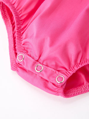 Girls hot pink romper with bow smocking embroidery, angle view showcasing stylish design and playful charm.