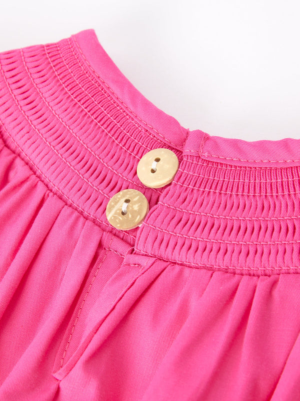 Girls hot pink romper with bow smocking embroidery, angle view showcasing stylish design and vibrant color.