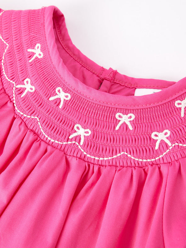 Girls hot pink dress with bow smocking embroidery, viewed from angle 3. Perfect for special occasions.