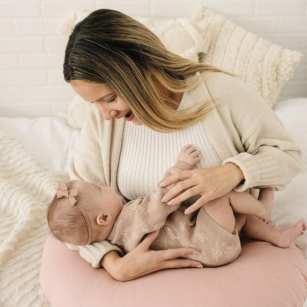 Blush nursing pillow for comfortable breastfeeding support, perfect for new moms and babies.