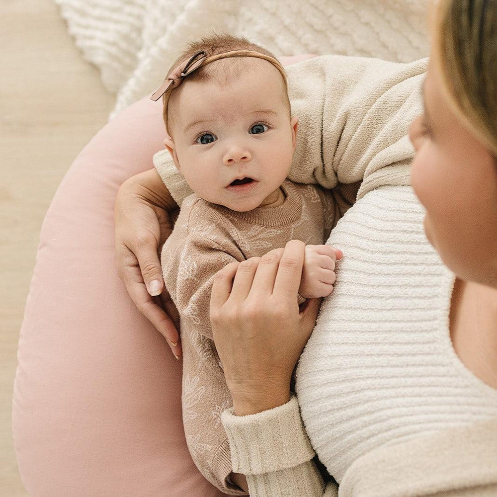 Blush nursing pillow cover for comfortable breastfeeding support, perfect for new moms.