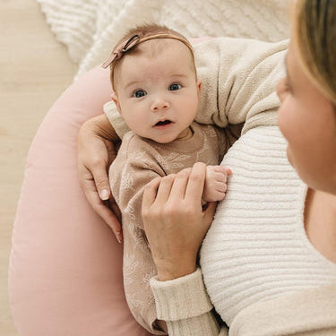 Blush nursing pillow for comfortable breastfeeding support, perfect for new moms and babies.