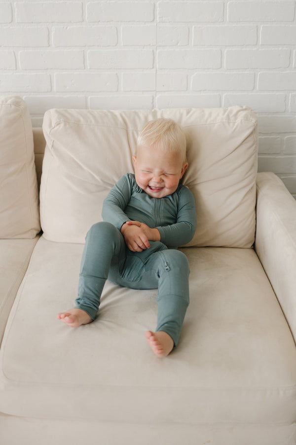 Solid Bamboo Zippy Pajamas in various colors, angle view showcasing soft, breathable fabric for babies.