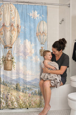 Mom holding her baby on the tub edge next to the Meadow Hot Air Balloons shower curtain